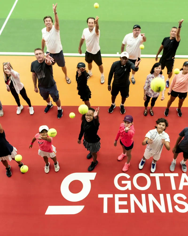 Academy group session on a red court with the GOTTA Tennis banner