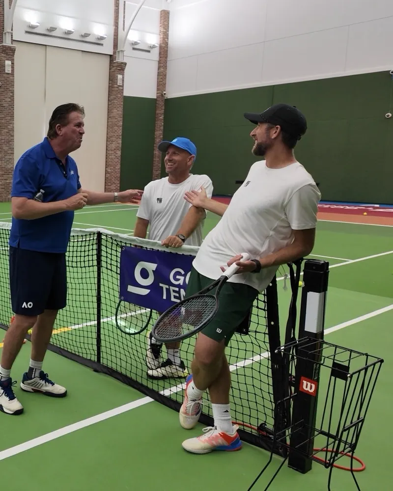 Three tennis coaches talking courtside at the net during a GOTTA Tennis session